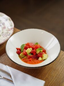 Colorful watermelon and cucumber salad with mint served in a bowl on wooden table.